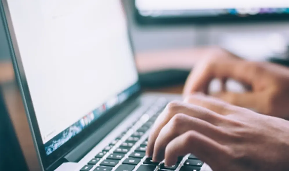 Fingers typing on a laptop